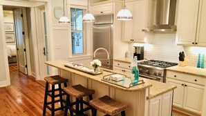 A kitchen with white cabinetry, a stainless steel refrigerator, a gas stove, and a large island with bar stools. - "The Lighthouse" in WaterColor. Pool, Walk to beach, 4 Bikes & WC amenities incl (Santa Rosa Beach)