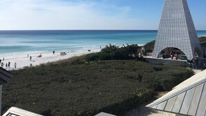 A beach with a modern pyramid-shaped building, clear blue sky, and sandy shore. - "The Lighthouse" in WaterColor. Pool, Walk to beach, 4 Bikes & WC amenities incl (Santa Rosa Beach)