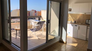 A room with a sliding glass door leading to an outdoor seating area with a table and chairs. - 3-room apt with terrace, AC, parking in Cap d'Agde, near beach and shops (Cap d'Agde)