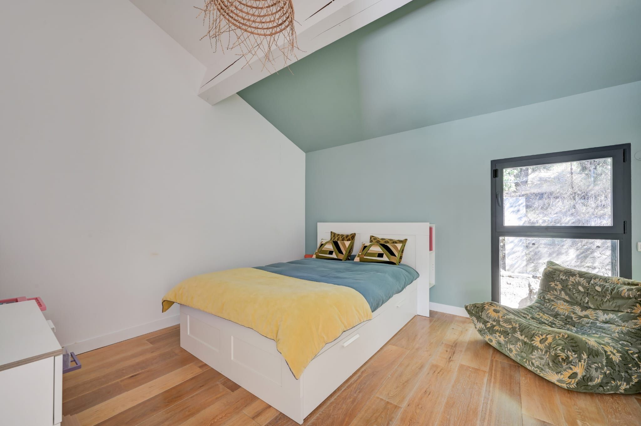 Een slaapkamer met een bed, een raam en een stoel.