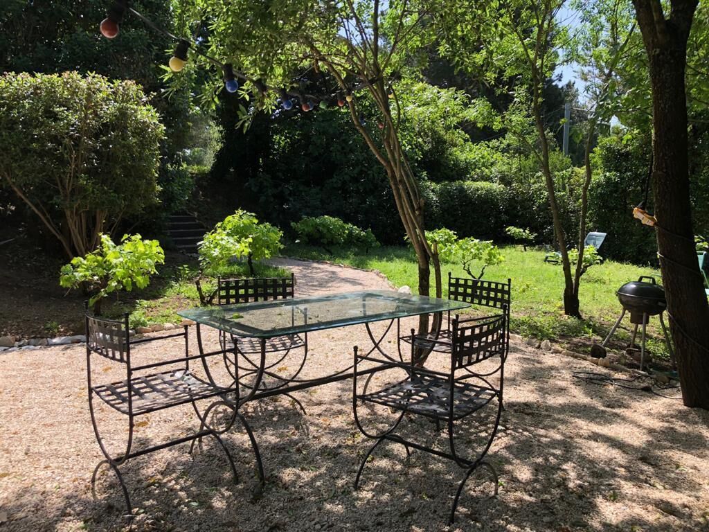 Een glazen tafel met metalen stoelen in een tuin.
