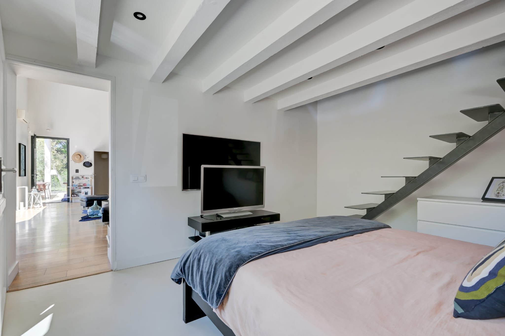 Un dormitorio moderno con una cama, un televisor y una escalera.