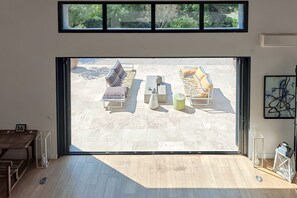 Een ruime kamer met een grote glazen schuifdeur die uitkomt op een terras.