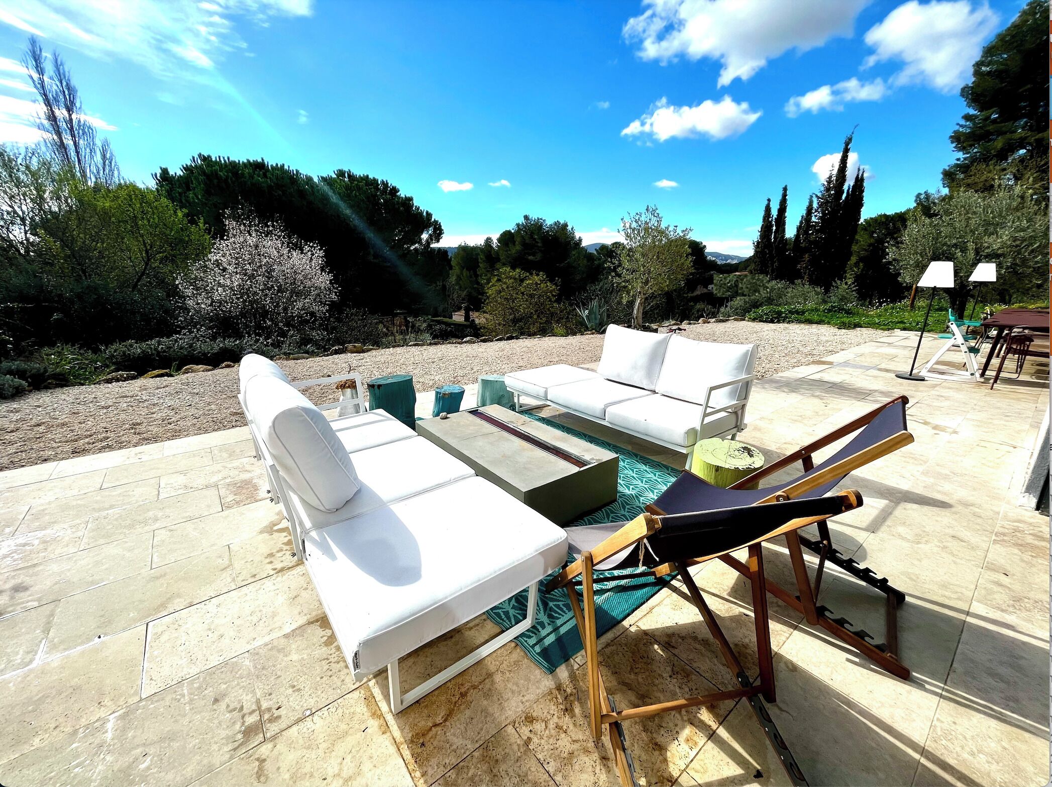 An outdoor patio with a white sofa set, a wooden table, and a pool table.