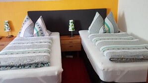A hotel room with two beds, each with a black headboard, a red carpet, and a small table with a lamp between the beds. - Pension Streng-Reinhardt (Ostfildern)