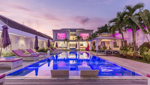A poolside area with lounge chairs and a pool, surrounded by a building with a bar and outdoor seating. - Exclusive Private 8 Bedroom Estate, 2 Huge Pools, Seminyak (Seminyak)