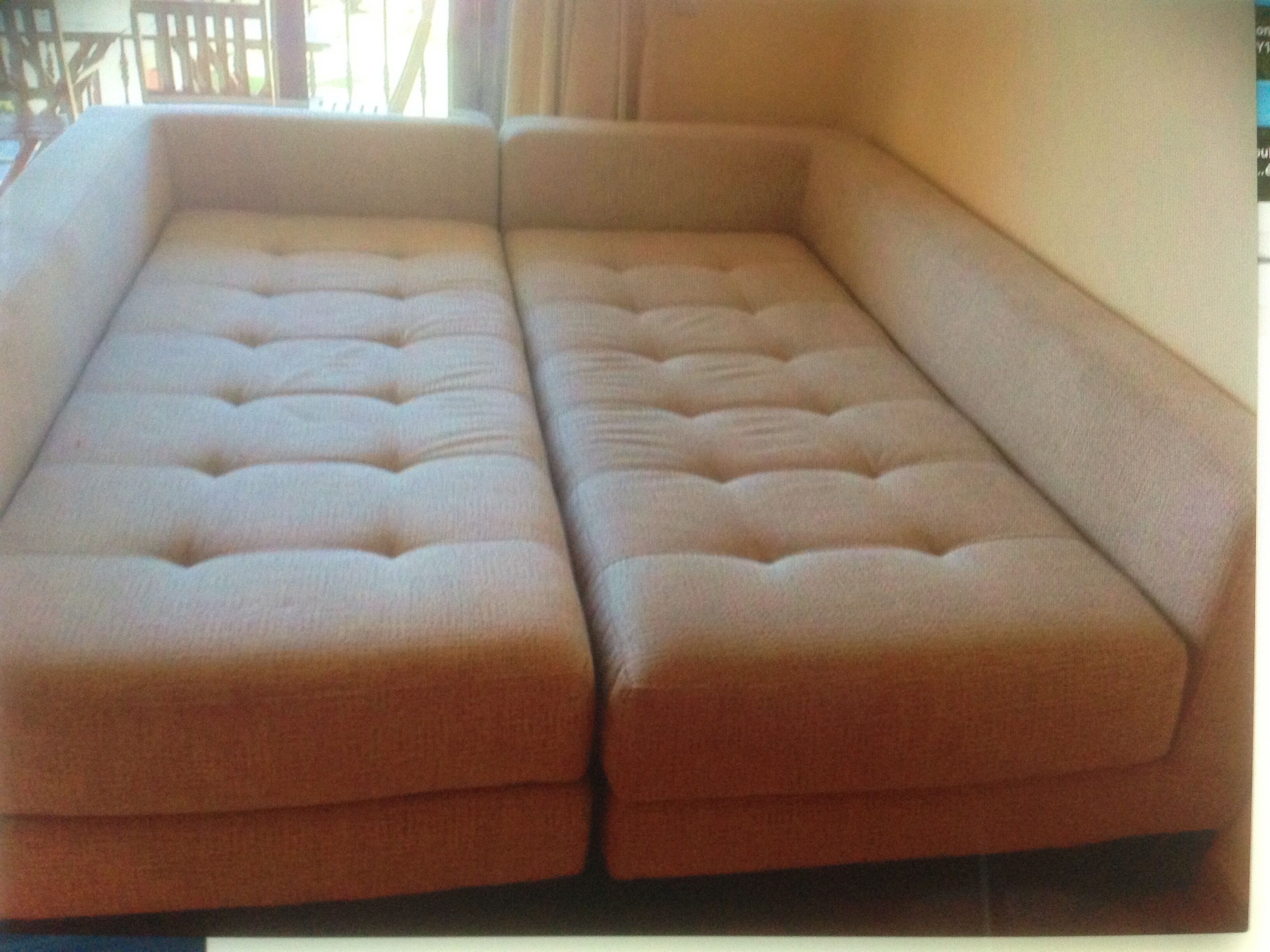 A sectional sofa with a tufted design, positioned against a wall.