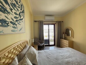 Una habitación de hotel con cama, una silla, cómoda y espejo, además de un gran mural de peces en la pared.
