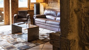Et hyggeligt interiør i en rustik hytte med en lædersofa, to lænestole, et sofabord og en lampe.