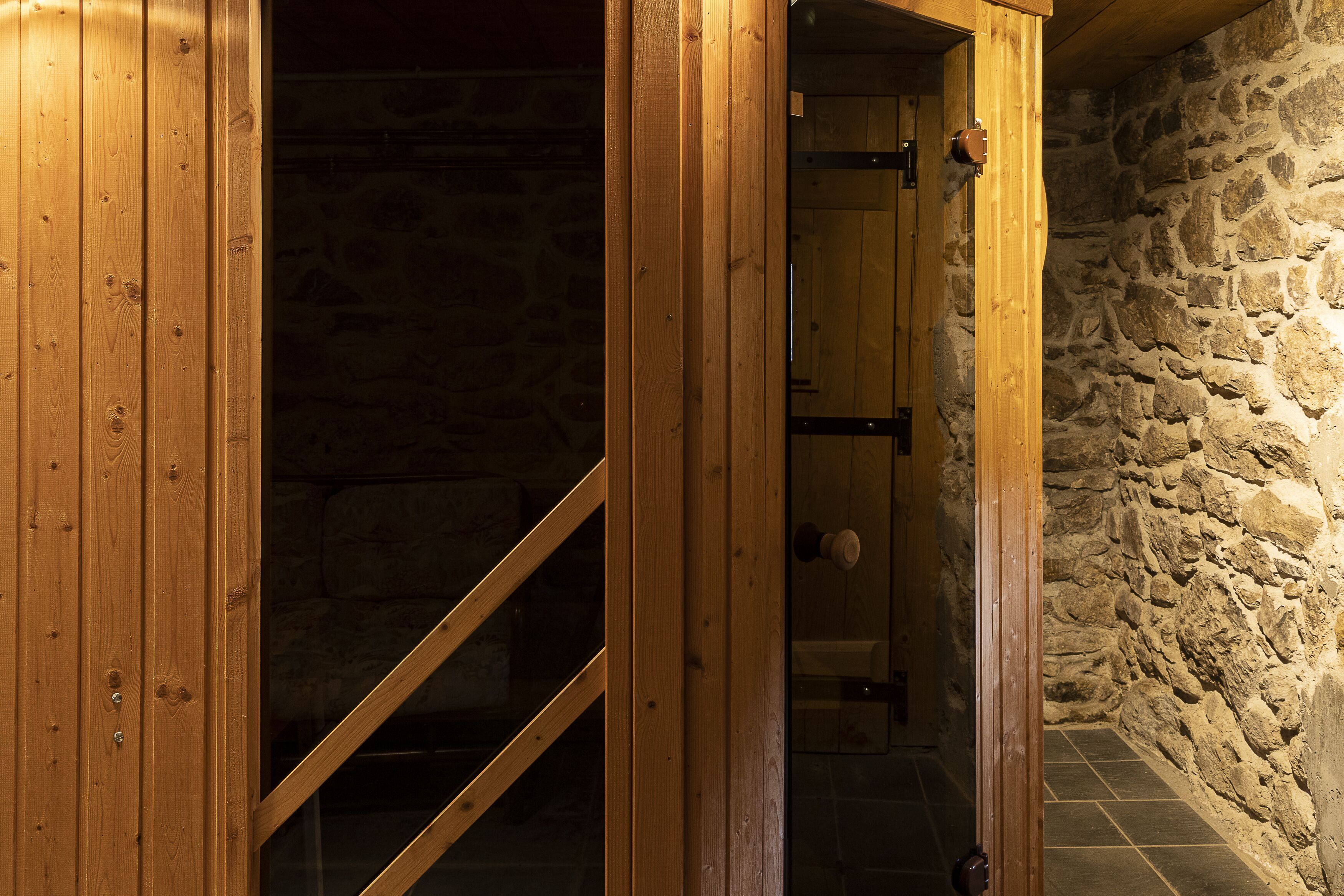 Una puerta de madera que da a una habitación con paredes de piedra y suelo de baldosas.