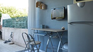 A compact kitchen with a refrigerator, a microwave, a small table, and two chairs. - Studio Cabine 3 Couchages à 50m de la Plage avec Terrasse et Parking - Le Grau d'Agde (Le Grau d'Agde)