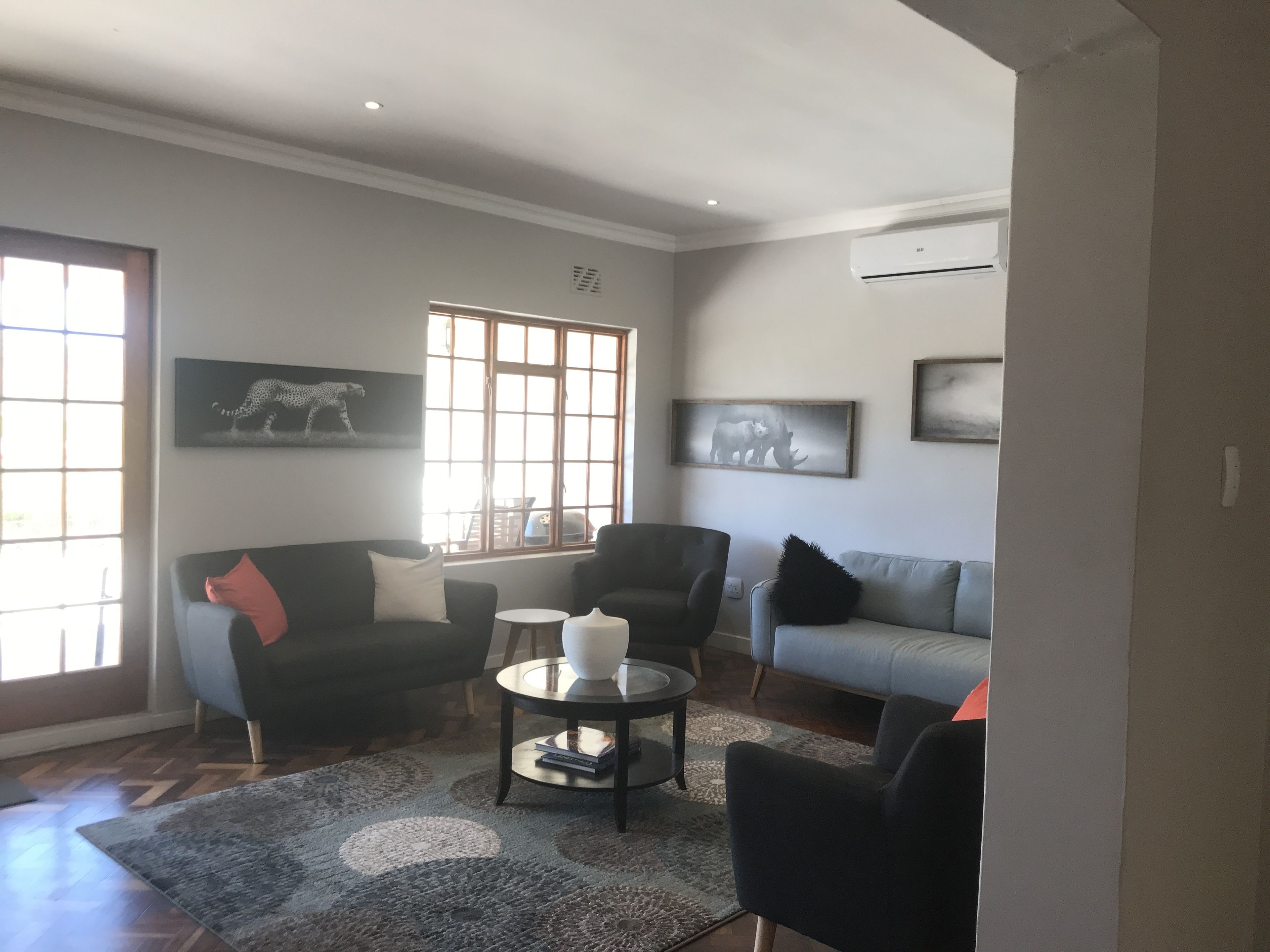Un salon comprenant un canapé, des fauteuils, une table basse et des œuvres d’art accrochées aux murs.