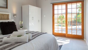 Een slaapkamer met een groot bed, een kledingkast, een raam met uitzicht op de omgeving en een deur naar buiten.