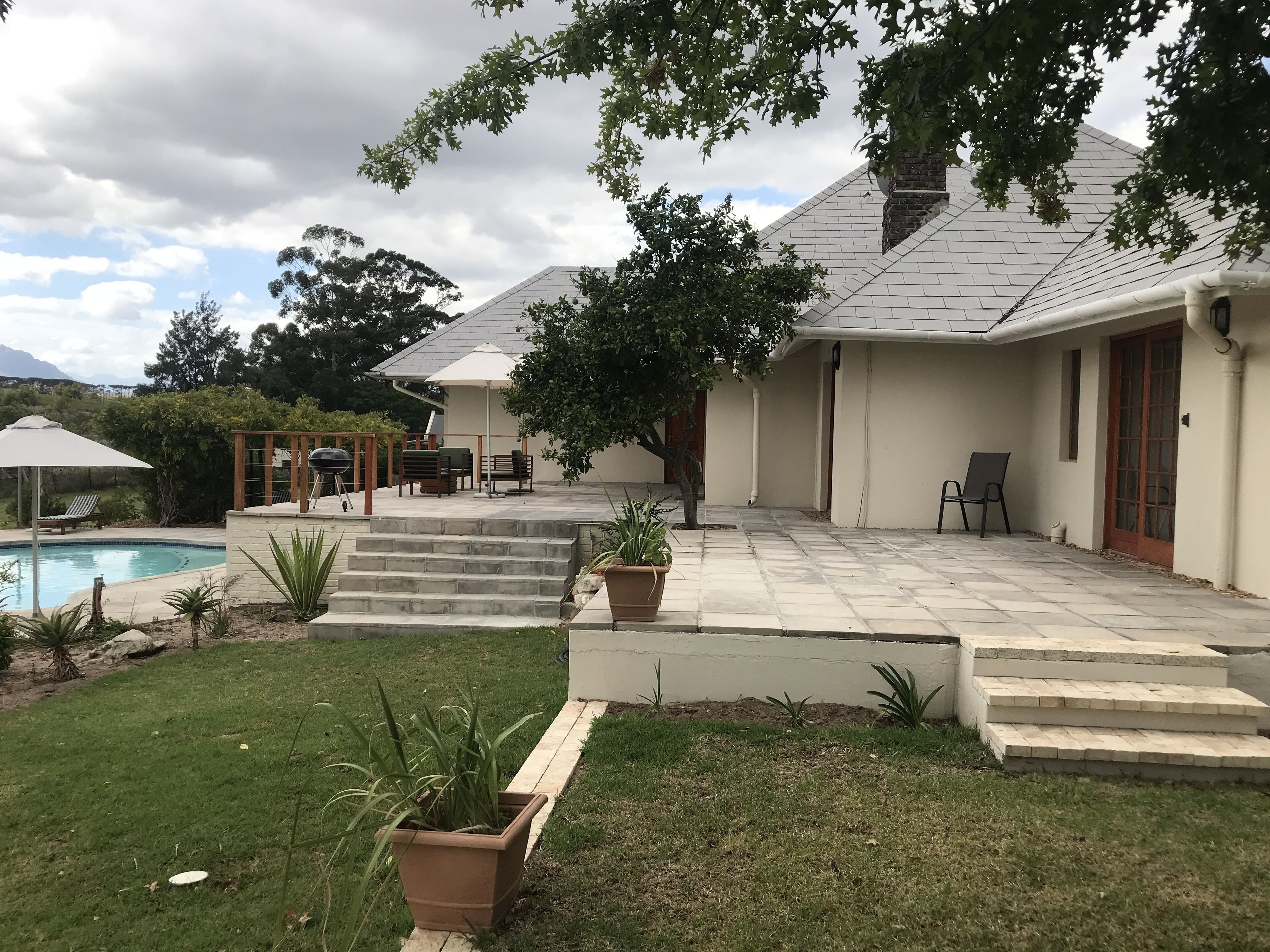A backyard with a swimming pool, outdoor seating, and a staircase leading to a covered patio area.
