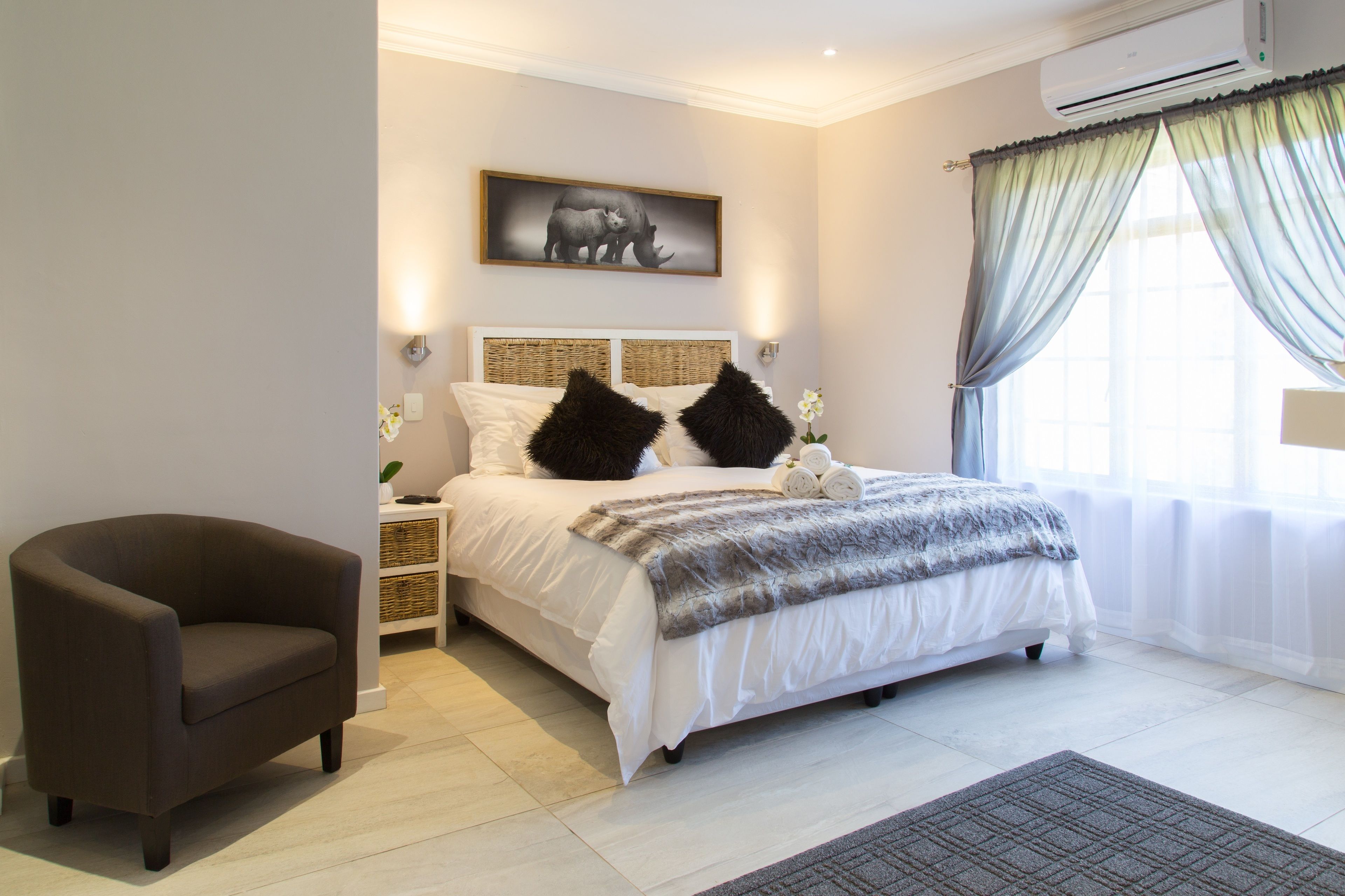 Een slaapkamer met een bed, een stoel en een wandairconditioner.