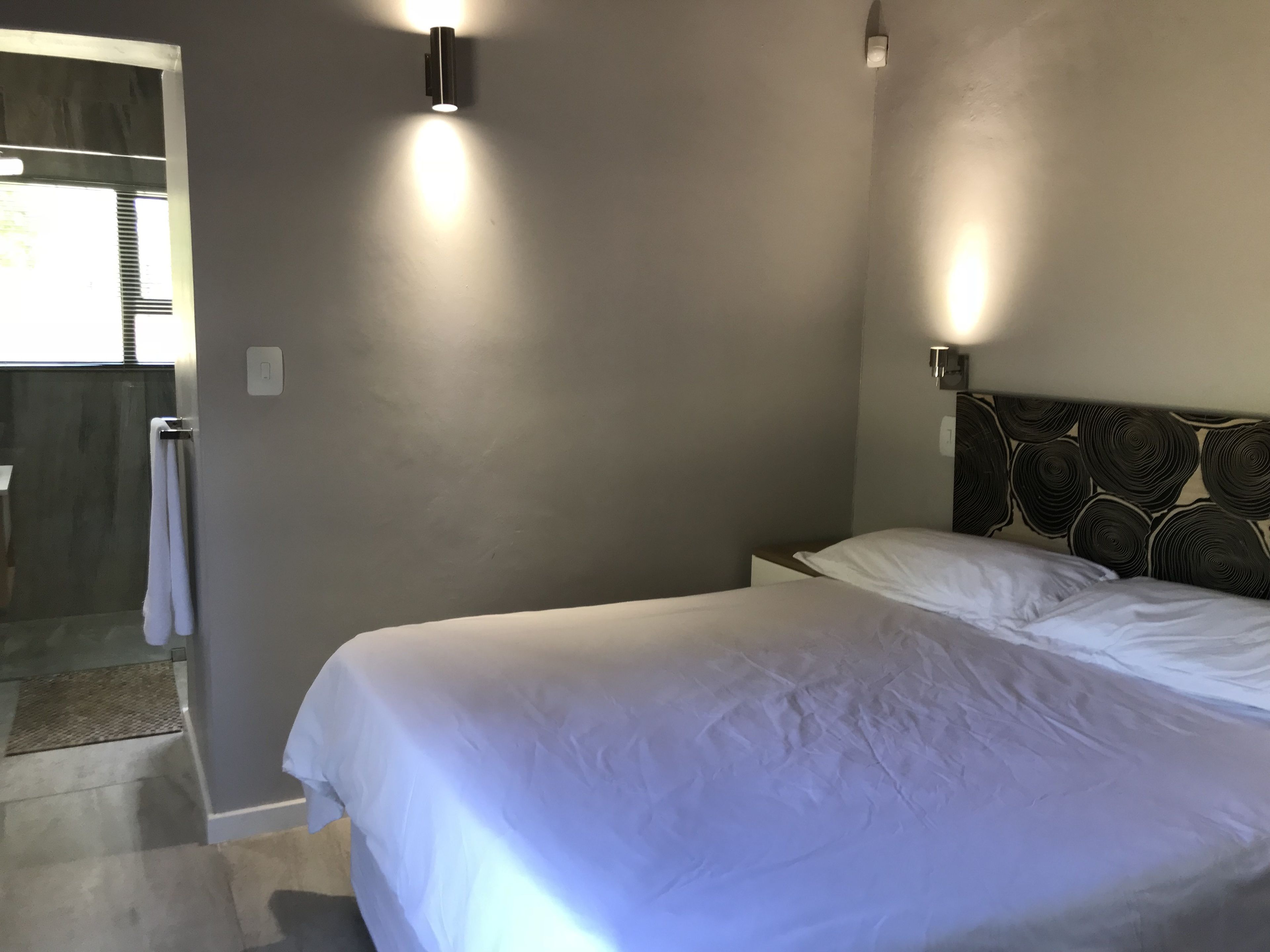 Un dormitorio con una cama, un cabecero con diseño circular y dos luces fijadas a la pared.