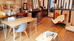 Une pièce chaleureuse avec une cheminée en briques, des meubles en bois et un fauteuil moderne.
