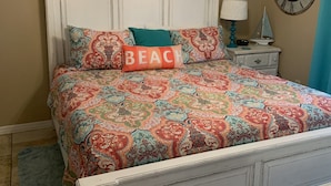A bedroom with a white bed, patterned bedding, a ceiling fan, a clock, and a small table with a lamp. - Cottage house Near Beach/All Attractions 2/2 Super Clean Private (Gulf Shores)