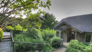A house with a wooden deck, a gravel pathway, and a variety of greenery including bushes and trees. - Townhome w/ Mtn Views & Club Access! Indoor Pool, Near Blowing Rock & Skiing (Boone)