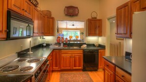 A kitchen with wooden cabinets, a stove, a dishwasher, and a window with a view of greenery outside. - Townhome w/ Mtn Views & Club Access! Indoor Pool, Near Blowing Rock & Skiing (Boone)