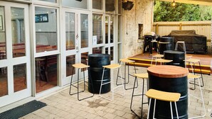 Un espace extérieur aménagé avec des tables et des chaises, un barbecue et une grande fenêtre donnant sur la rue.