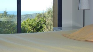 A bedroom with a large window overlooking a mountainous landscape.