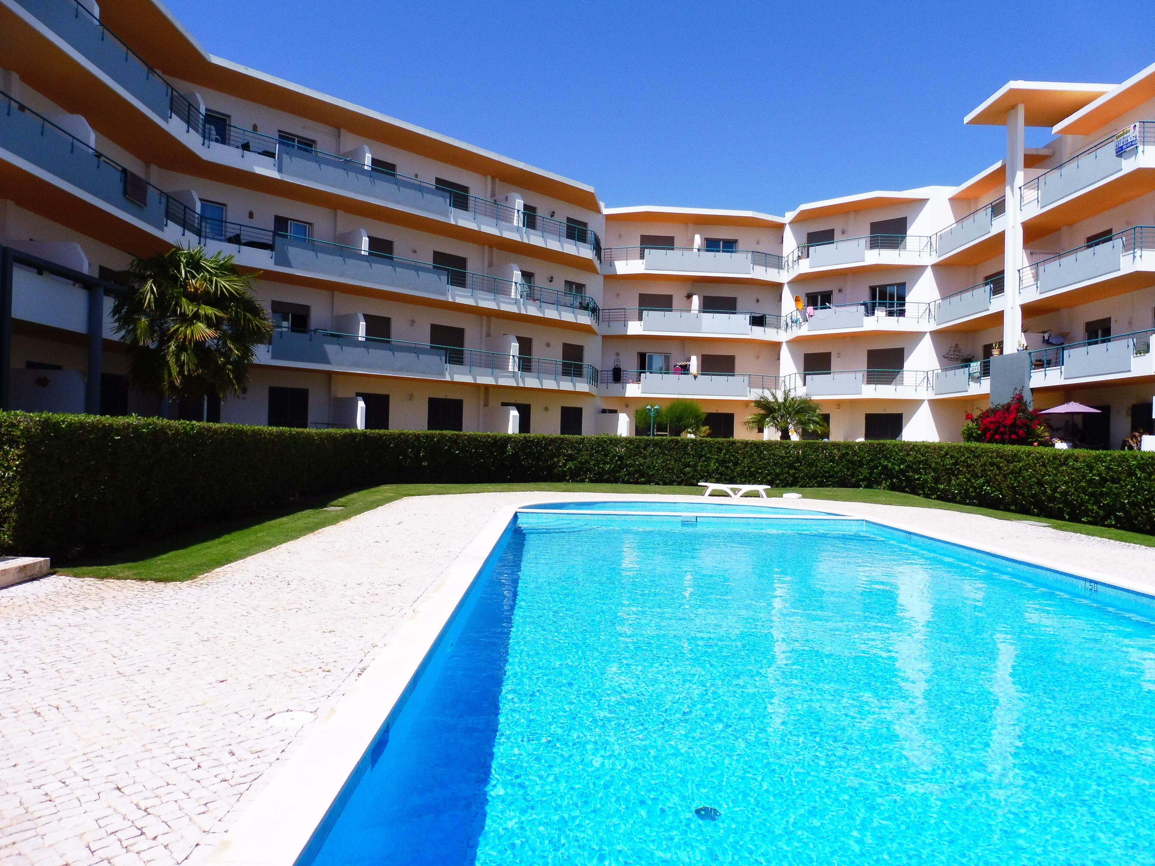 Et hotel med flere etager, swimmingpool, altaner og en velholdt have.