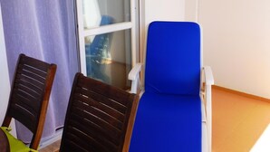 Een balkon met twee houten stoelen en een blauwe loungestoel.