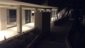 Een modern gebouw met een overdekt terras, een trap en een goed verlichte ingang.