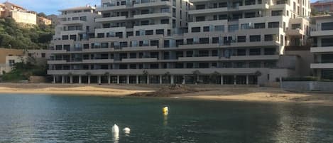 A multi-story hotel with balconies, located near a beach.