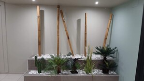 Een moderne binnentuin met bamboeplanten en diverse groen op een betegeld oppervlak.
