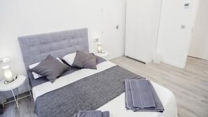Une chambre moderne avec un grand lit, deux tables de chevet et une armoire.