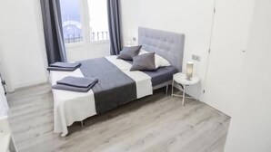 Une chambre à coucher moderne avec un lit, des tables de chevet et une fenêtre avec des rideaux.