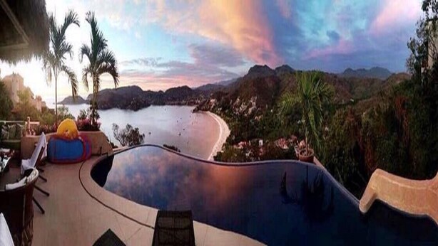A swimming pool with a view of a beach and mountains.