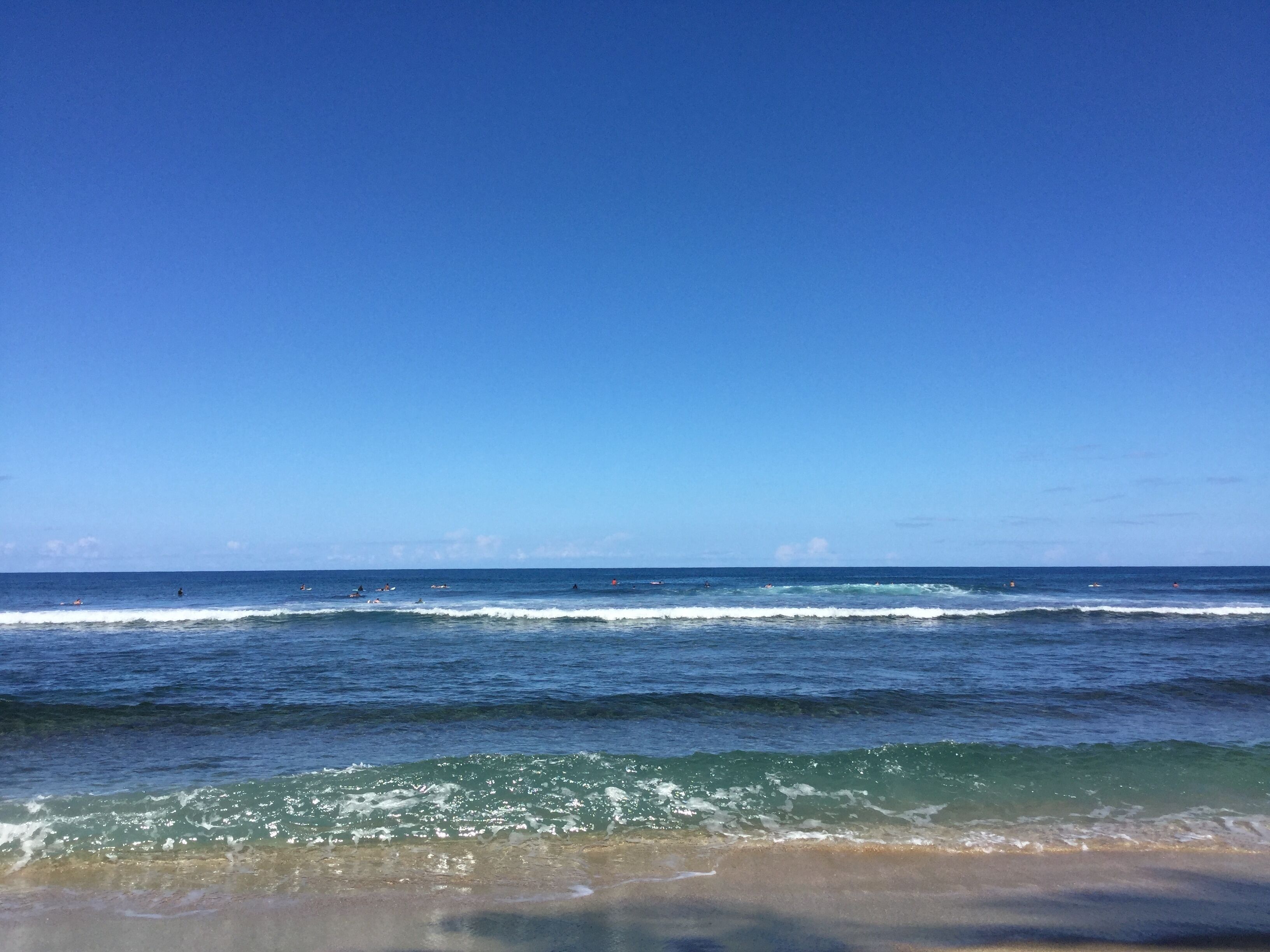 A beach with waves and a clear sky.