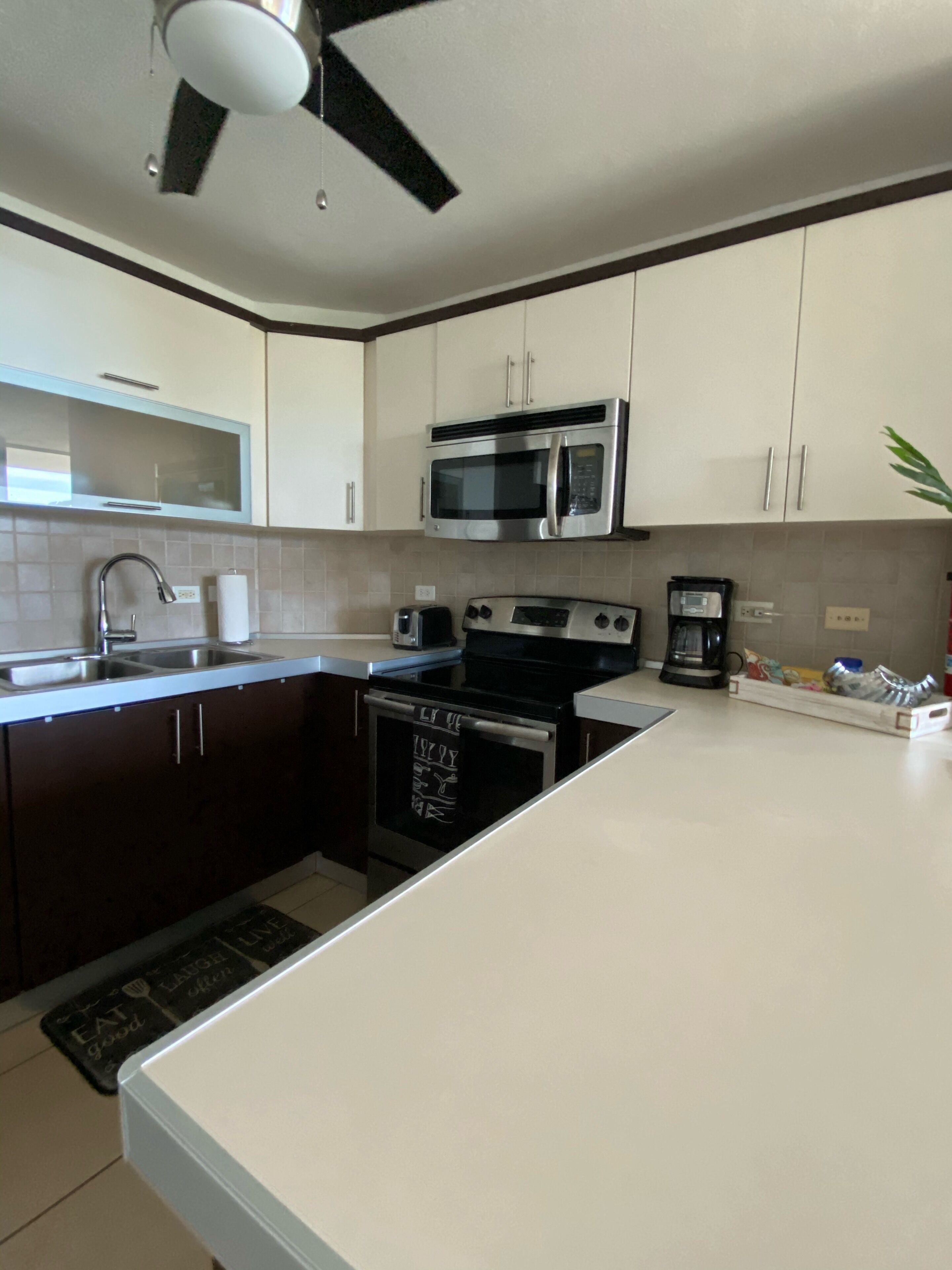 A modern kitchen with white cabinets, a microwave, a stove, and a sink.