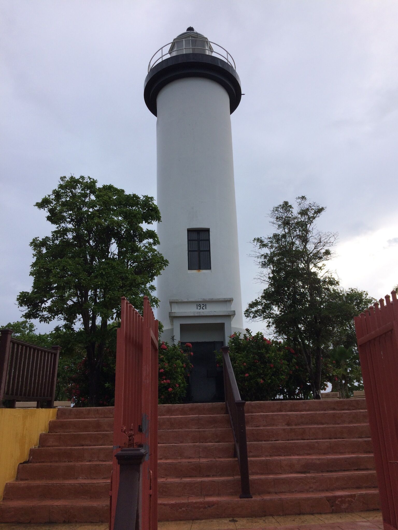 A lighthouse with a cylindrical white tower, a small window, and the number 1921 on its base.