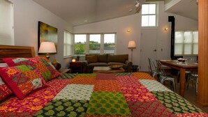 Um quarto com uma cama grande, um sofá, uma mesa de jantar e duas luminárias.