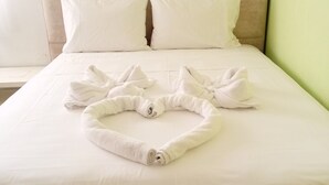 Un lit bien fait, avec une tête de lit, des draps blancs et une serviette soigneusement posée sur le lit.