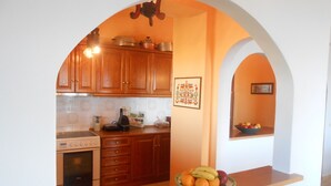 Une cuisine avec des meubles de rangement en bois, une cuisinière et un panier de fruits posé sur le plan de travail.