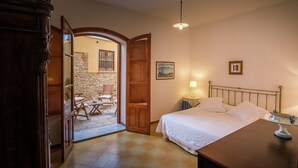 A bedroom with a bed, bedside table, lamp, and a view of an outdoor patio area. - Charming Villa by the sea, wifi and cooking class free! (Termini Imerese)