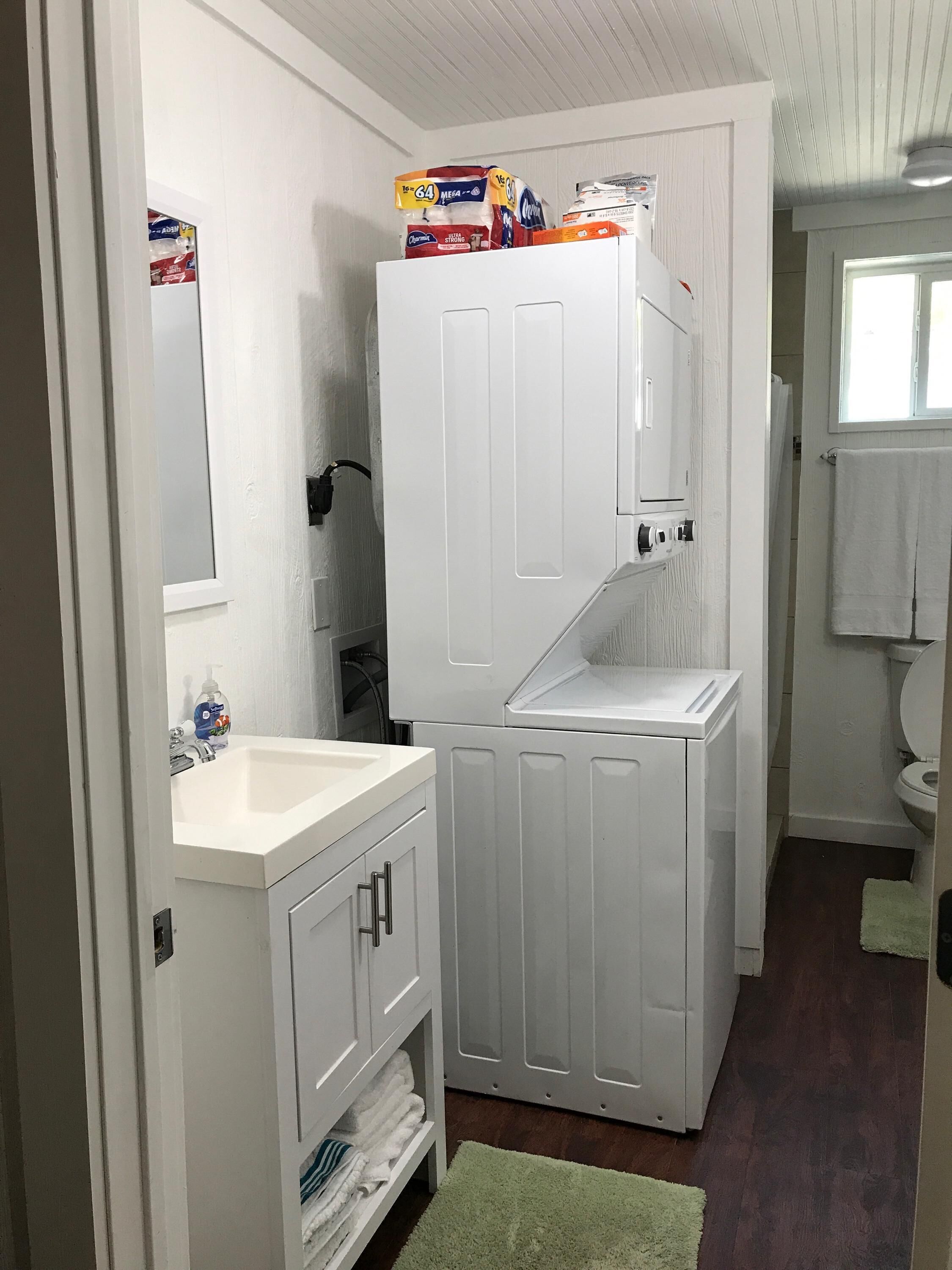 A compact bathroom with a white vanity, a sink, and a toilet. There are storage cabinets and a mirror above the vanity.