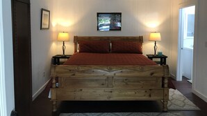 A bedroom with a wooden bed, two bedside tables with lamps, a framed picture on the wall, and a window.