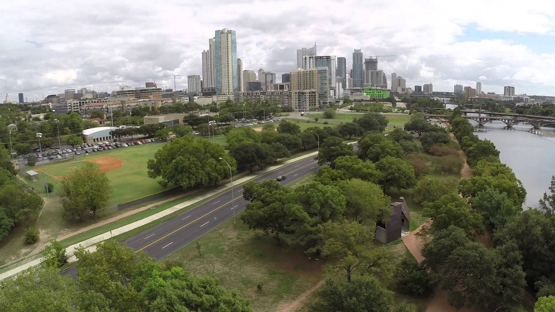 A cityscape with a river, a bridge, and a baseball field.