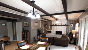 Un comedor con una mesa y sillas de madera, una chimenea y un sofá al fondo.