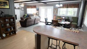Amplia sala de estar con una gran mesa de comedor de madera, un sofá y una estantería.