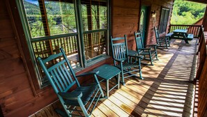 Eine Holzhütte mit Veranda, ausgestattet mit Schaukelstühlen und einem Picknicktisch.