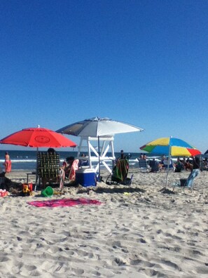 Una playa con sombrillas, sillas de playa y una torre de salvavidas.