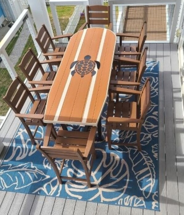 A wooden deck with a table and chairs, surrounded by a blue patterned rug.
