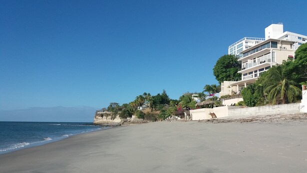 A beach with a clear sky, a sandy shore, and buildings with balconies overlooking the sea. - Guicci Resort - Playa Corona beach  (San Carlos)